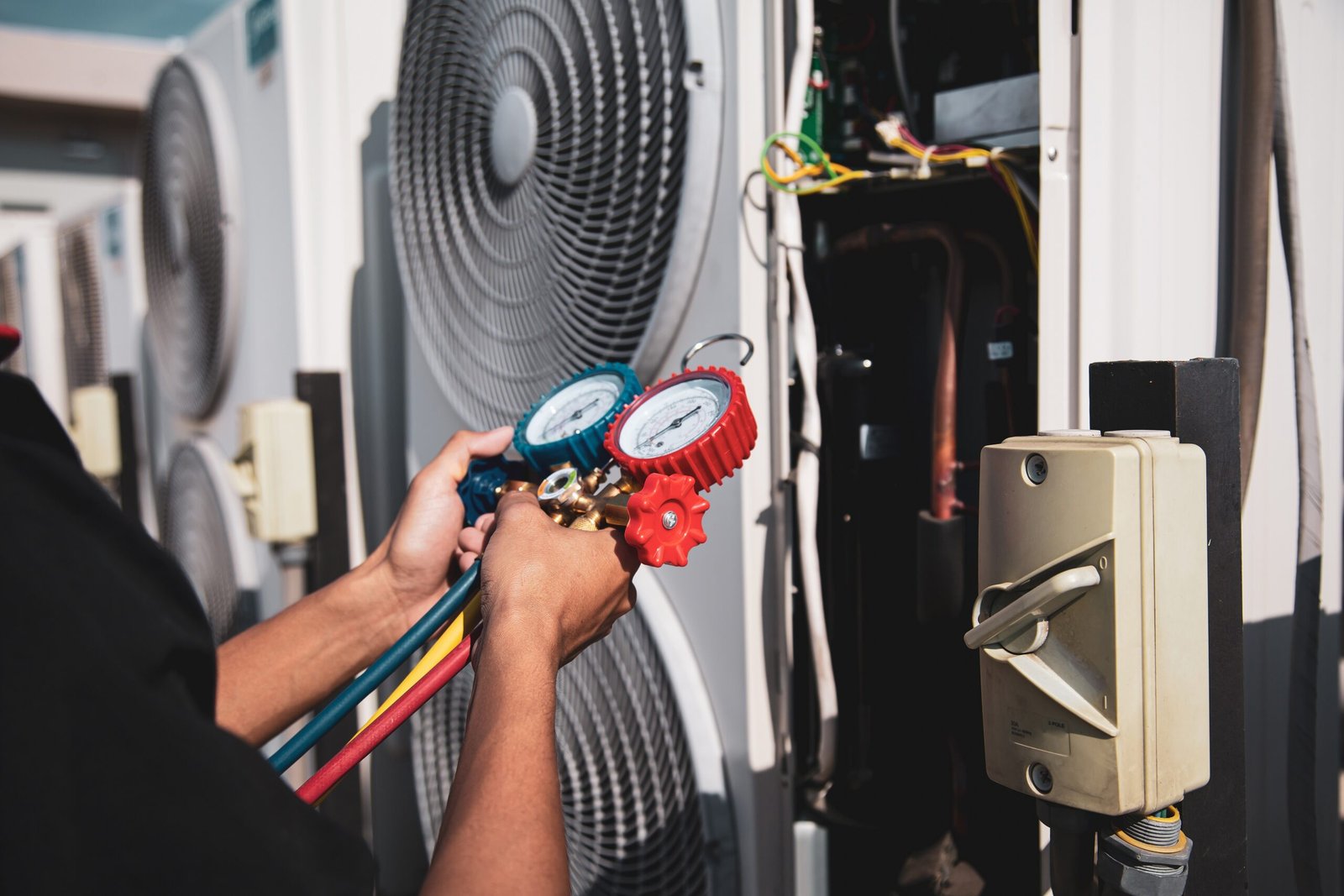 Heat and Air Conditioning, HVAC system service technician using measuring manifold gauge checking refrigerant and filling industrial air conditioner after duct cleaning maintenance outdoor compressor.
