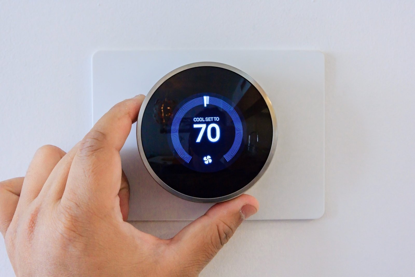 hands adjusting a smart thermostat
